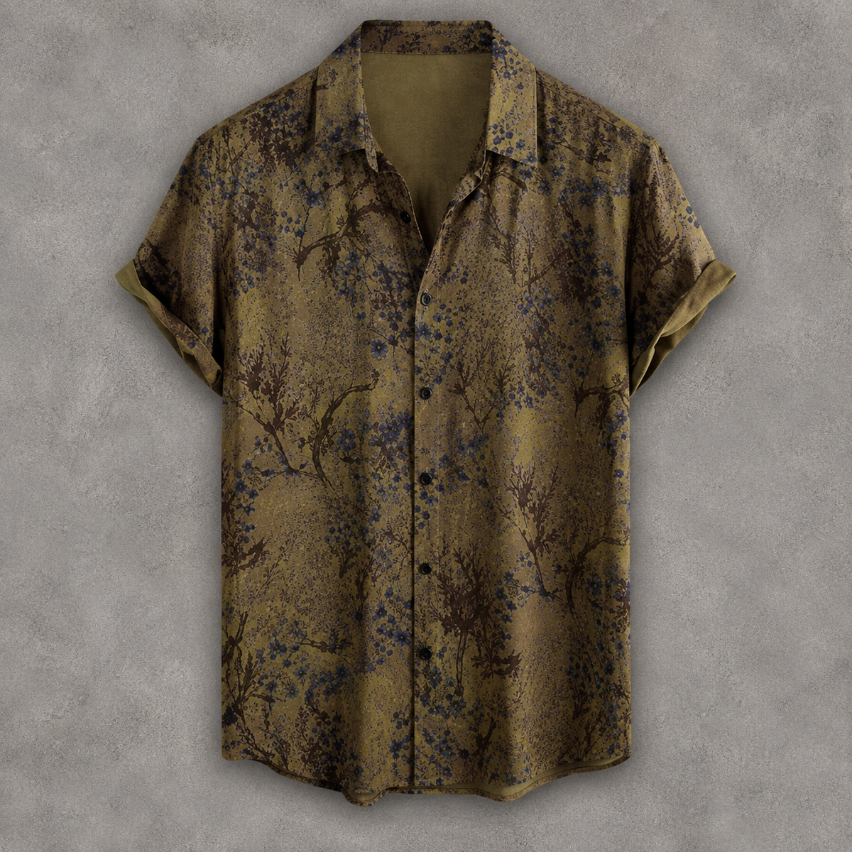 A short-sleeve button-up shirt with a muted olive-brown base and an allover abstract floral or branch-like print in dark blue and black, displayed against a textured gray background.