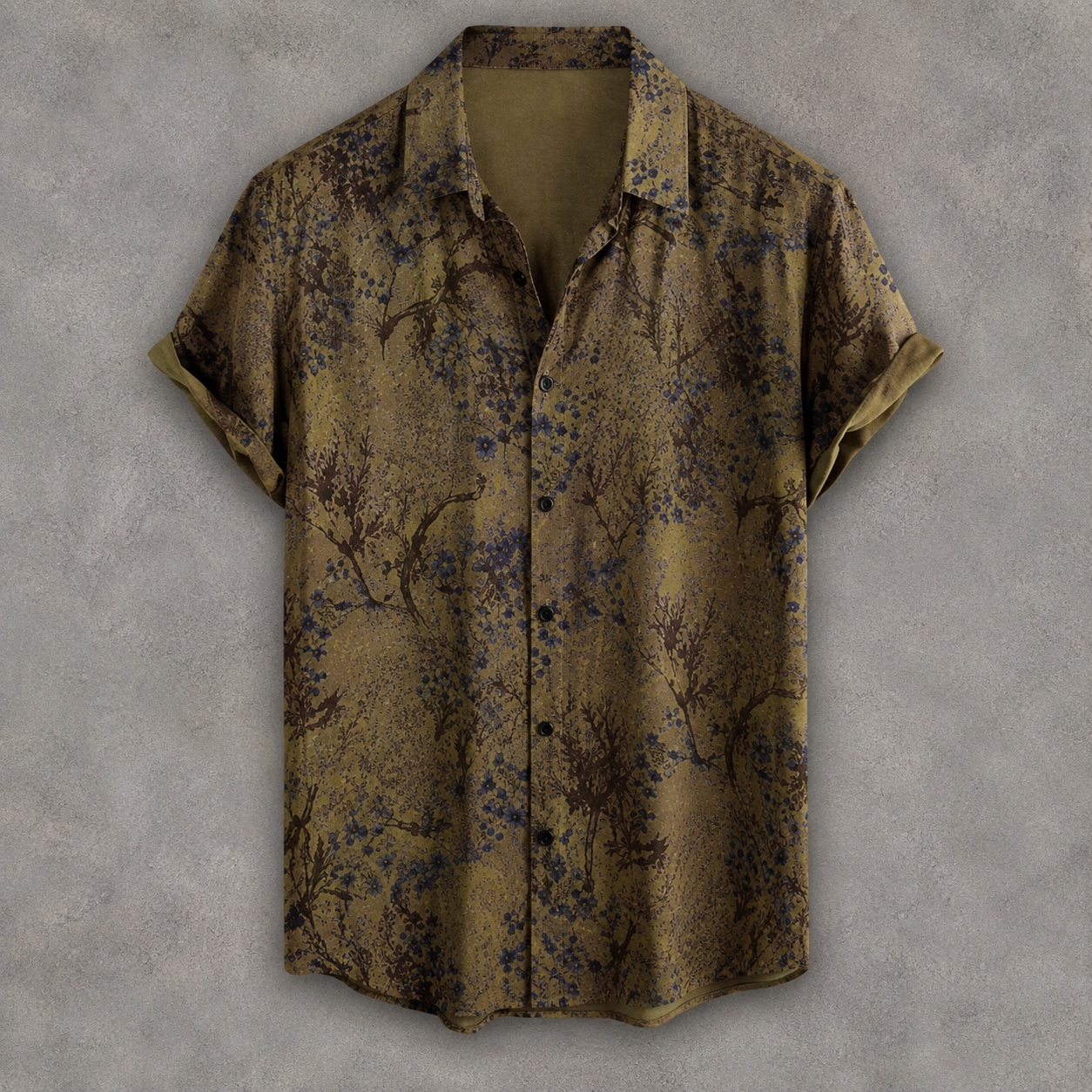 A short-sleeve button-up shirt with a muted olive-brown base and an allover abstract floral or branch-like print in dark blue and black, displayed against a textured gray background.