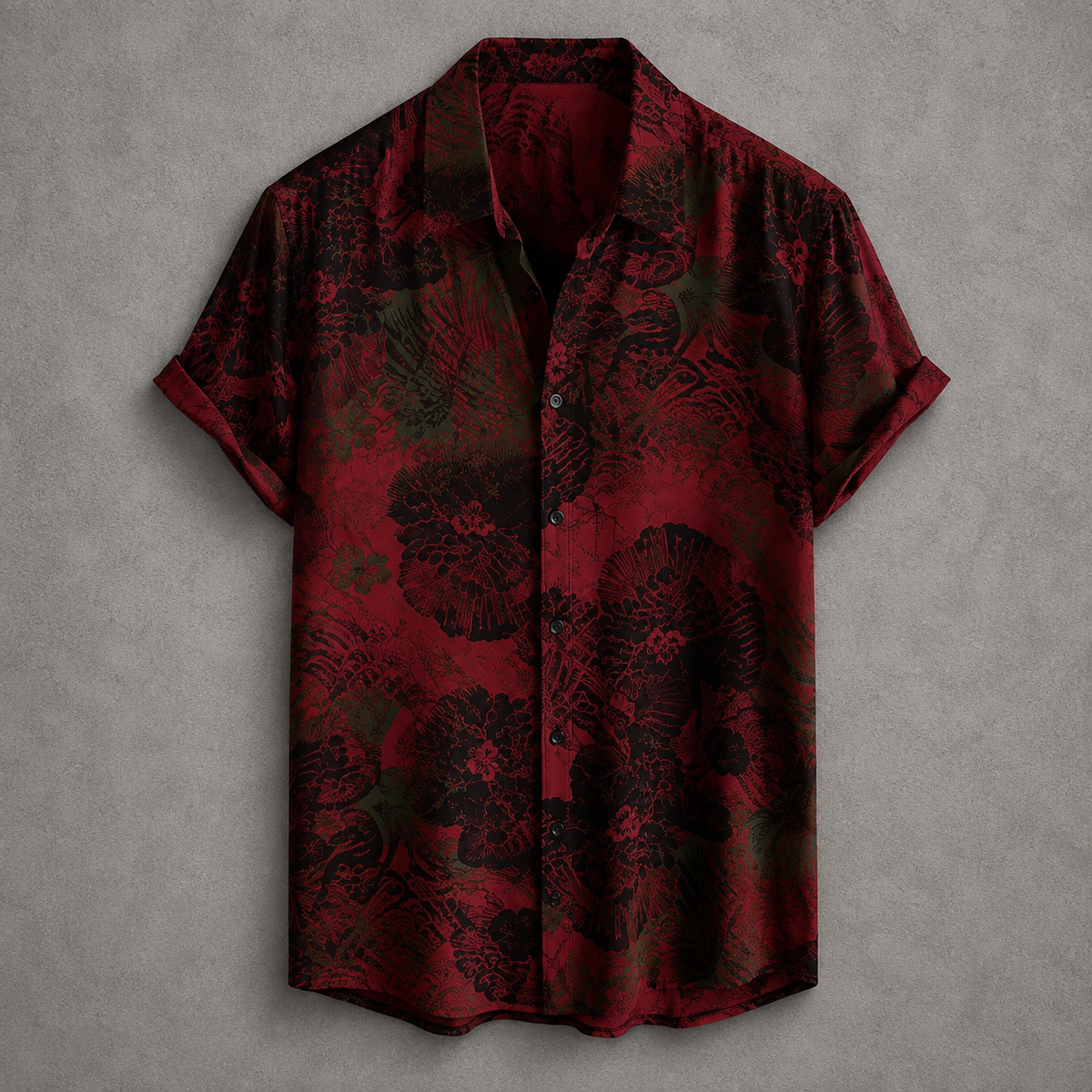 A short-sleeve button-up shirt with a red and black tropical floral pattern, displayed flat against a textured gray background.