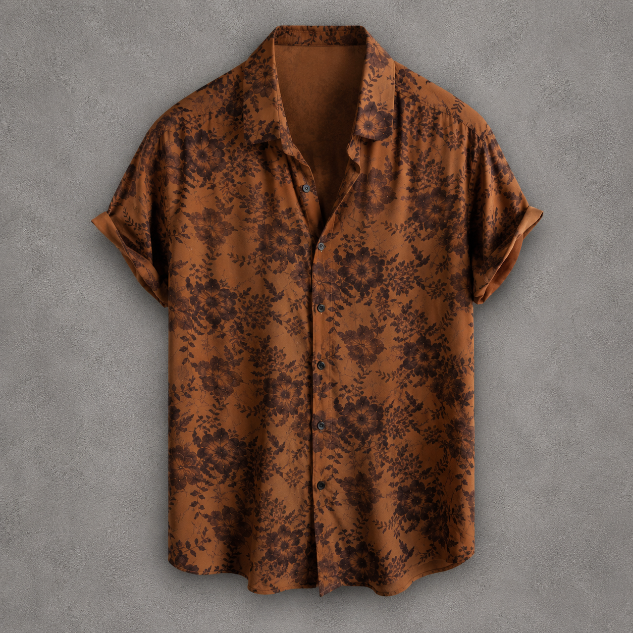 A short-sleeve button-up shirt in a warm brown base with a dark brown floral pattern, displayed flat against a textured gray background.