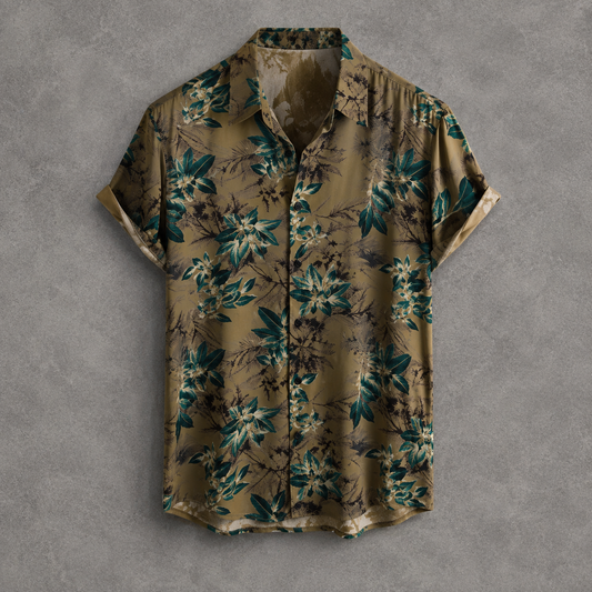 A short-sleeve button-up shirt with a tropical floral print in olive green, teal, and beige, laid flat against a textured gray background.