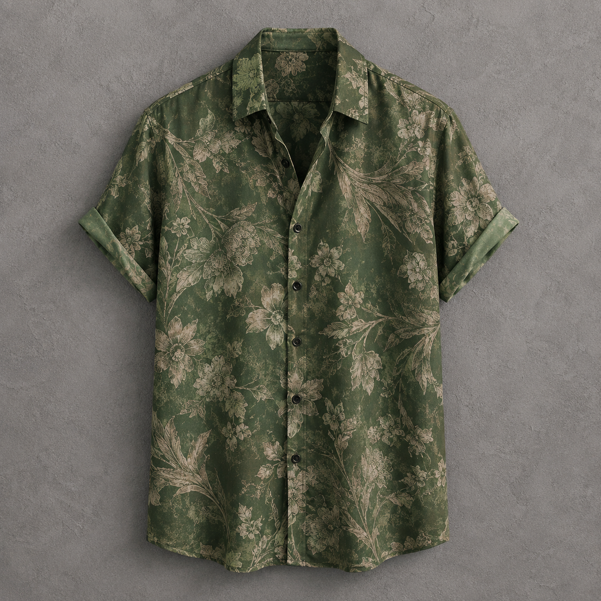A short-sleeve button-up shirt in olive green with a beige floral pattern, laid flat against a textured gray background.