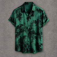 A short-sleeve button-up shirt in emerald green with a black floral and botanical print, displayed flat against a textured gray background.