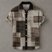 A short-sleeve button-up shirt with a textured geometric pixelated pattern in shades of brown, beige, and black, featuring a solid black collar and button placket with white buttons, displayed flat against a gray background.