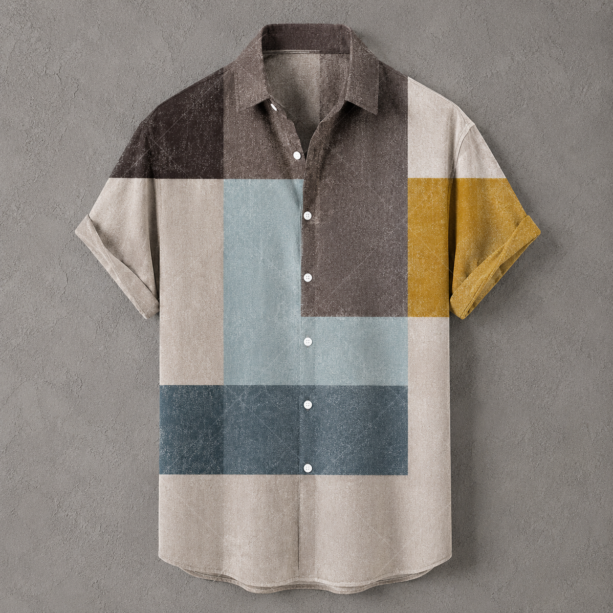 A short-sleeve button-up shirt with a geometric block pattern in beige, brown, light blue, dark blue, and mustard yellow, displayed against a textured gray background.