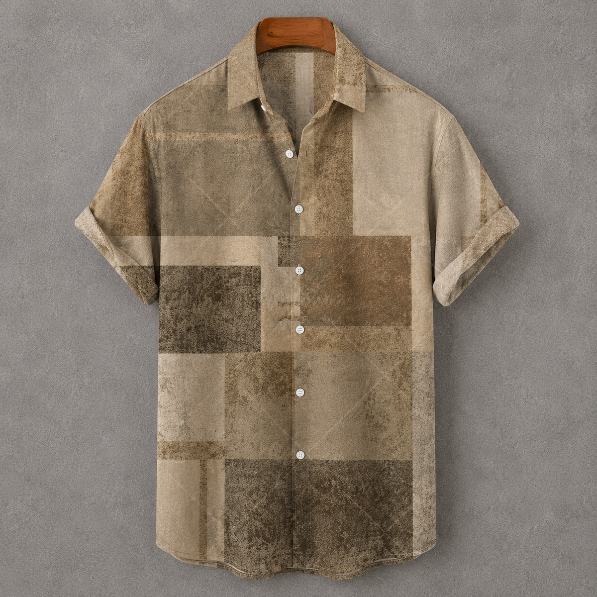A short-sleeve button-up shirt with a distressed patchwork pattern in shades of beige, brown, and tan, hanging on a wooden hanger against a textured gray background.