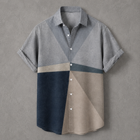 A men's short-sleeve button-up shirt with a geometric color-block pattern in gray, beige, navy blue, and dark teal, displayed flat against a textured gray background.