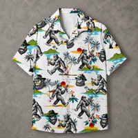 A short-sleeve button-up camp shirt with a white base and a detailed graphic print of gorillas in tropical beach scenes, laid flat on a textured gray background.