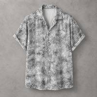 A short-sleeve button-up shirt with a black and white abstract textured pattern, displayed flat against a gray concrete-textured background.
