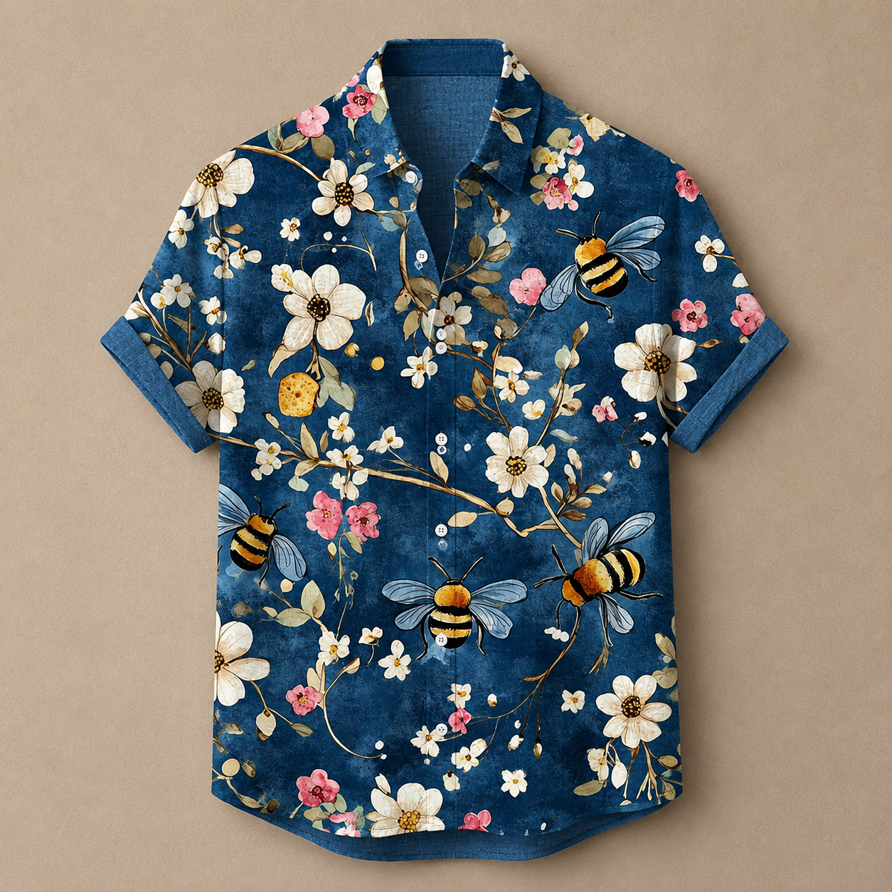 A short-sleeve button-up shirt with a dark blue base, featuring a detailed print of white flowers, pink blossoms, yellow and black bumblebees, and small green leaves, laid flat against a solid beige background.