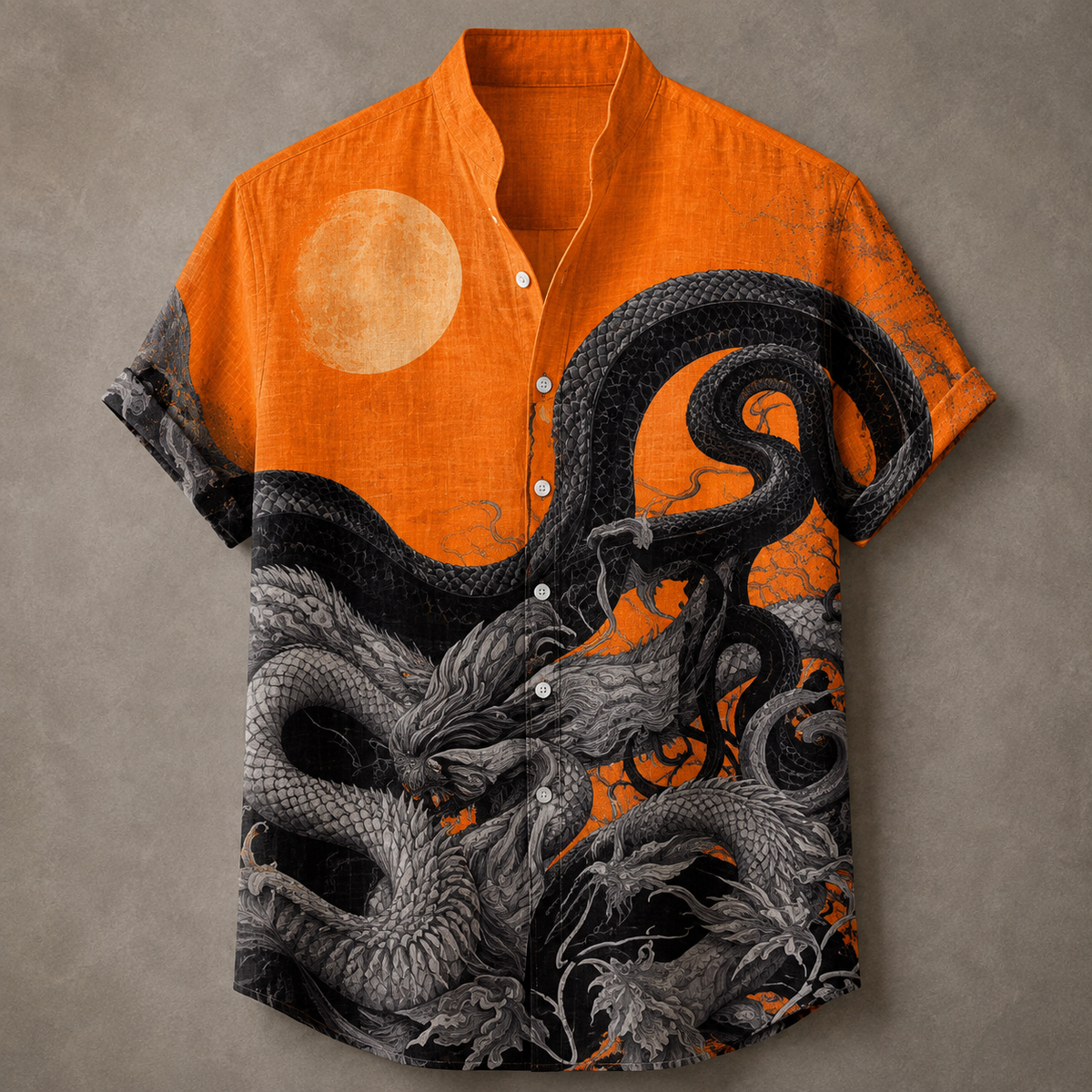 A short-sleeve button-up shirt with a vibrant orange base, featuring a large pale moon graphic on the upper chest and a detailed black and gray dragon illustration across the lower half, displayed flat against a textured gray background.