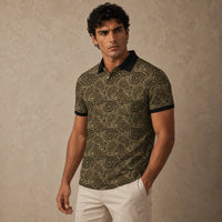 Man wearing a patterned polo shirt and white pants against a beige background