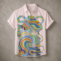 A short-sleeve button-up shirt in a very light pink or off-white color, featuring a large, vibrant, multicolored psychedelic tiger graphic printed on the front. The shirt is displayed flat against a textured gray concrete wall.