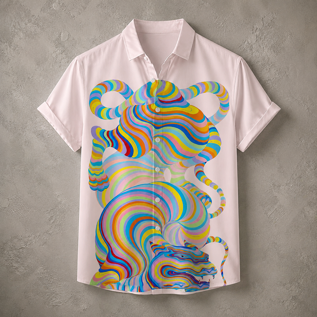 A short-sleeve button-up shirt in a very light pink or off-white color, featuring a large, vibrant, multicolored psychedelic tiger graphic printed on the front. The shirt is displayed flat against a textured gray concrete wall.