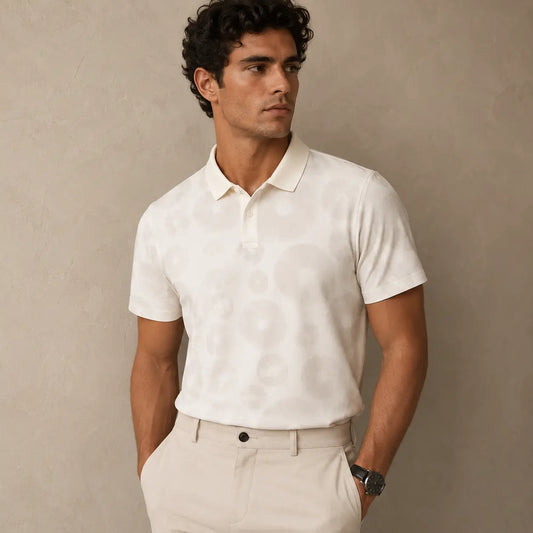 Man wearing a white polo shirt and beige pants against a plain background