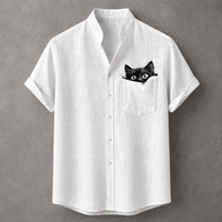 A white short-sleeve button-up shirt with a black cat peeking out of the chest pocket, displayed against a textured gray background.