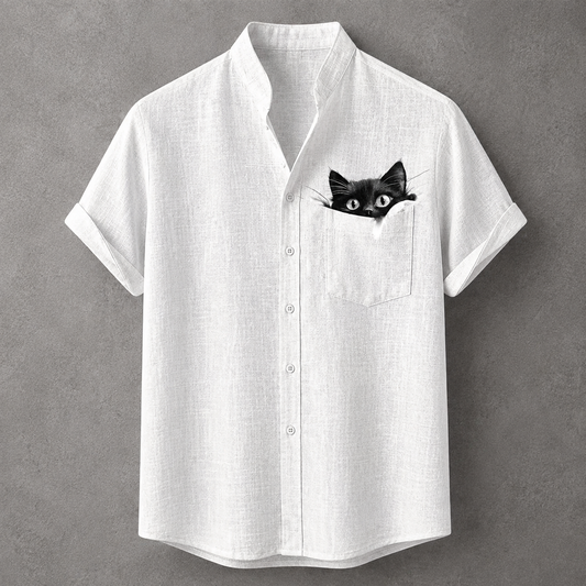 A white short-sleeve button-up shirt with a black cat peeking out of the chest pocket, displayed against a textured gray background.