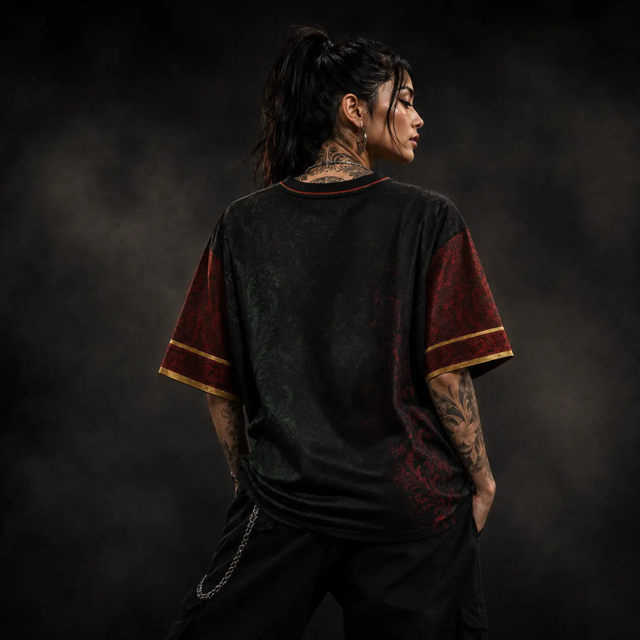 Person wearing a black and red shirt with tattoos on a dark background