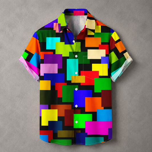 A short-sleeve button-up camp shirt with a vibrant, multicolored geometric pixelated pattern on a black background, displayed flat against a textured gray backdrop.