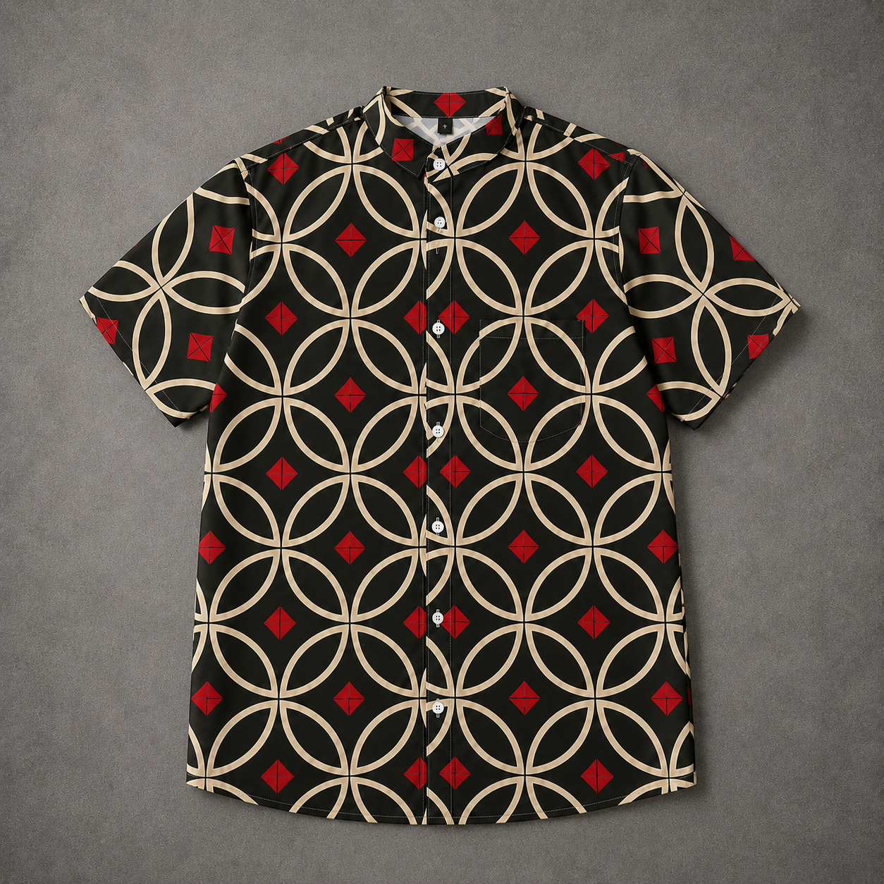A short-sleeve button-up camp shirt with a black base, beige interlocking circle pattern, and red diamond accents, laid flat on a textured gray background.