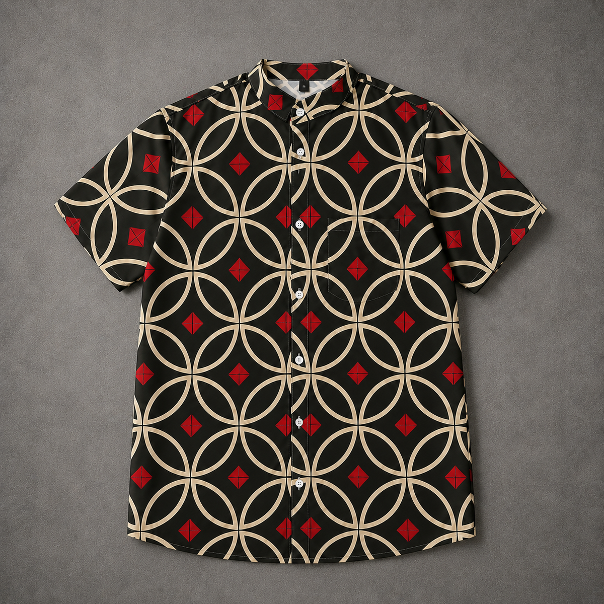 A short-sleeve button-up camp shirt with a black base, beige interlocking circle pattern, and red diamond accents, laid flat on a textured gray background.