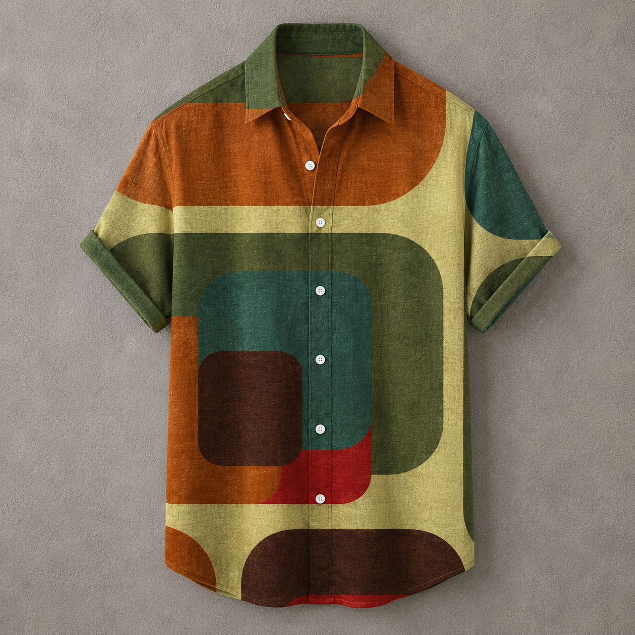 A short-sleeve button-up shirt with an abstract geometric pattern in olive green, rust orange, teal, cream, brown, and red, displayed flat against a textured gray background.