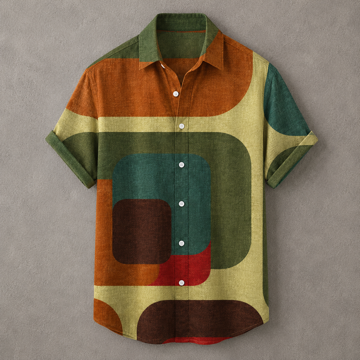 A short-sleeve button-up shirt with an abstract geometric pattern in olive green, rust orange, teal, cream, brown, and red, displayed flat against a textured gray background.