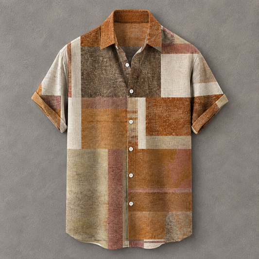 A short-sleeve button-up shirt with a textured patchwork design in earthy tones of brown, rust orange, beige, and muted pink, displayed against a textured gray background.
