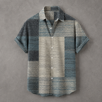 A short-sleeve button-up shirt with a textured patchwork design in muted blue, gray, and beige tones, laid flat against a textured gray background.