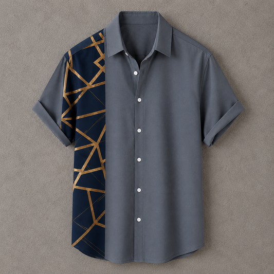 A short-sleeve button-up shirt laid flat on a textured gray background. The shirt is primarily slate gray with a contrasting dark navy panel on the wearer's left side featuring a geometric gold line pattern.