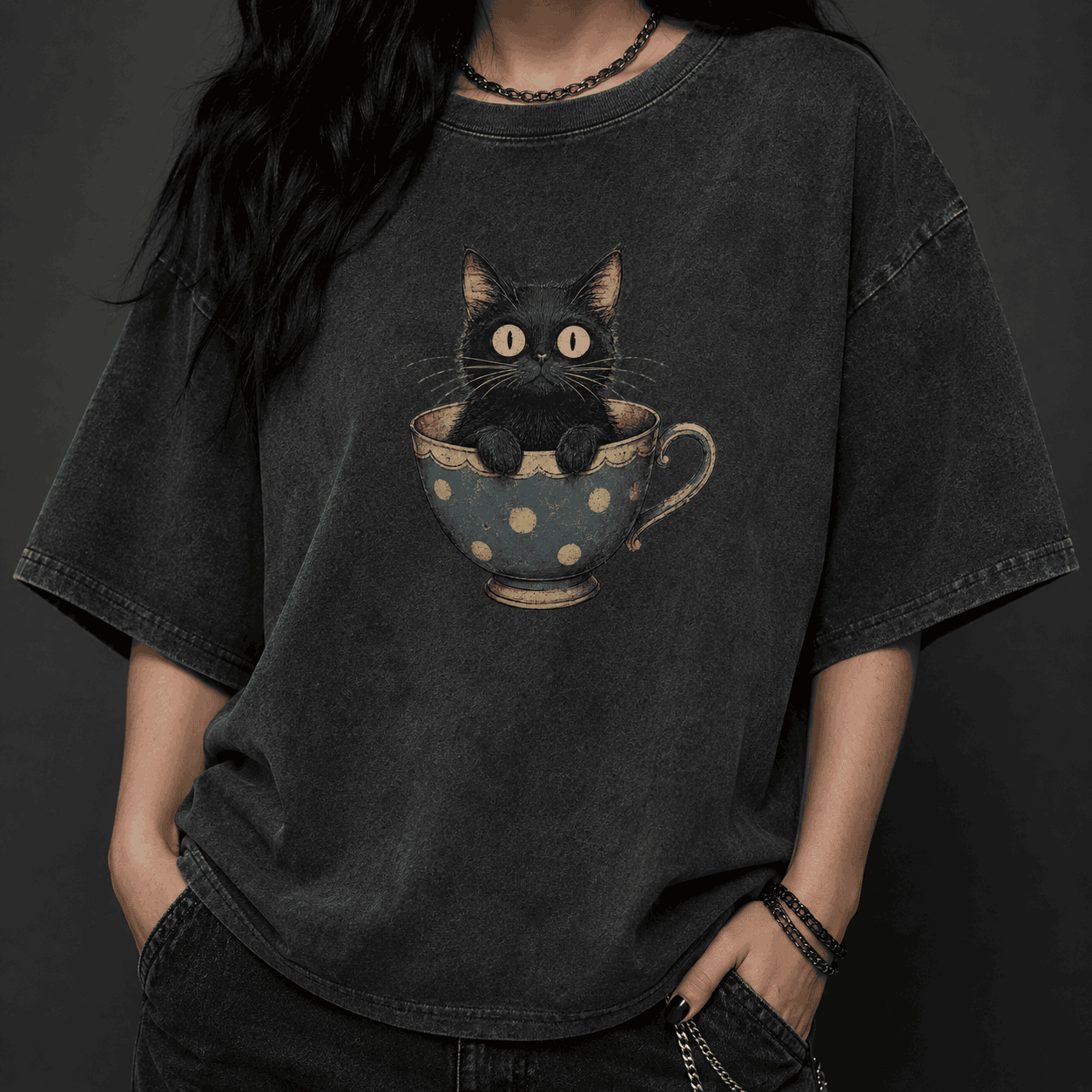 Person wearing a black t-shirt with a graphic of a cat in a teacup on a dark background