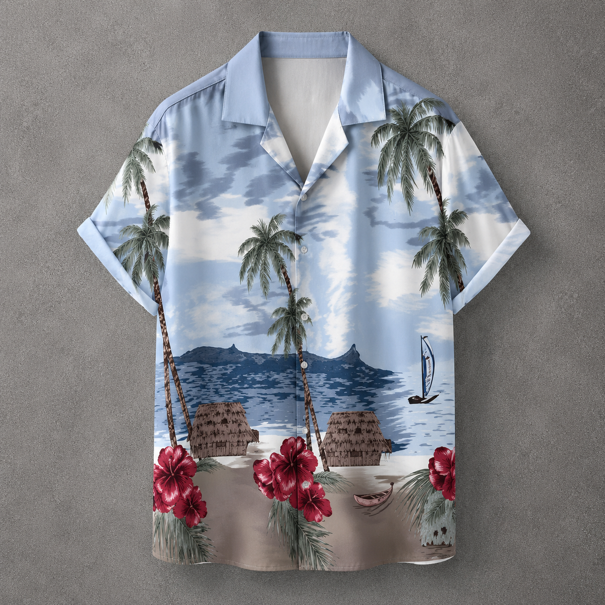 A short-sleeve button-up Hawaiian shirt with a tropical beach print, featuring palm trees, blue water, mountains, beach huts, and red hibiscus flowers, displayed against a textured gray background.