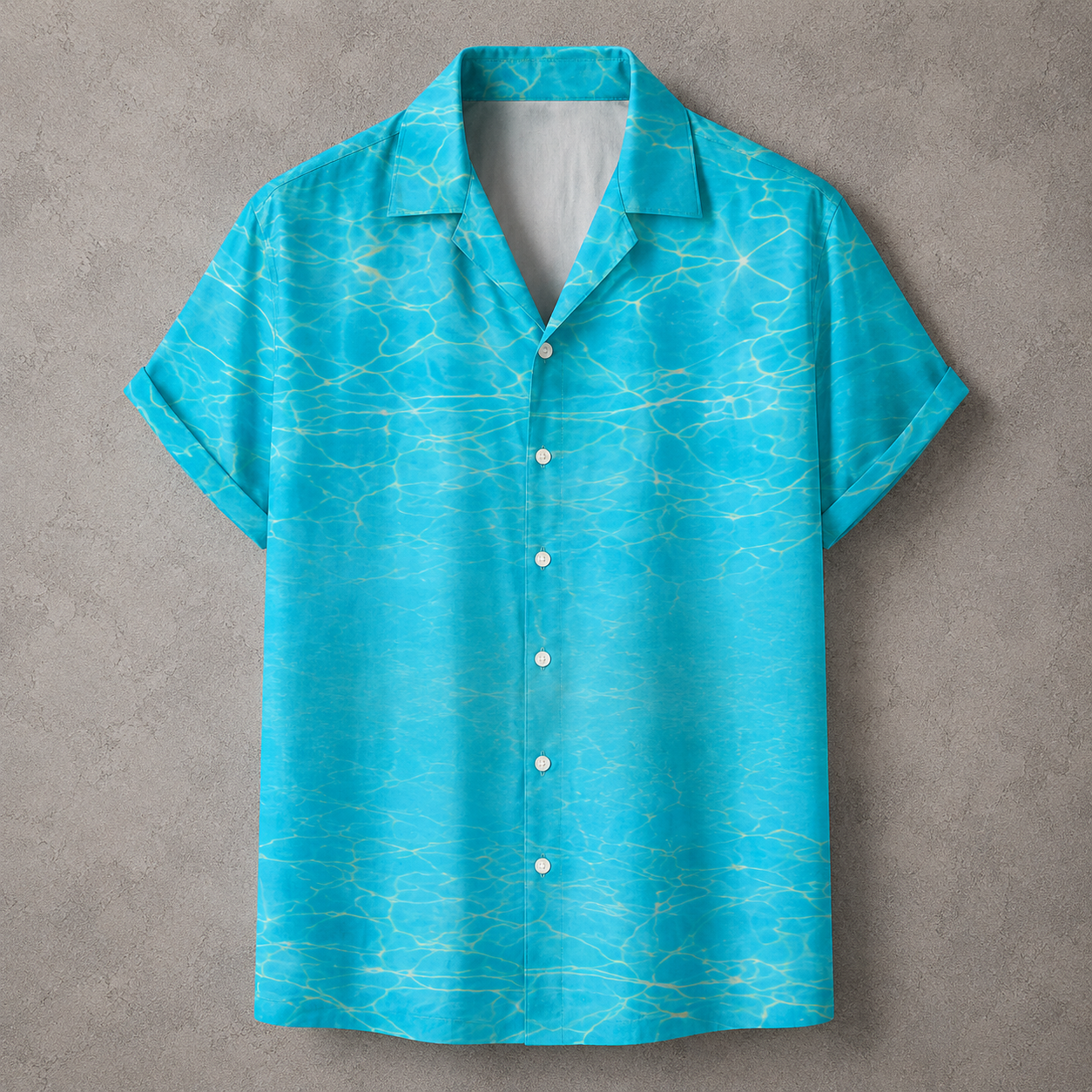 A short-sleeve button-up camp shirt in bright turquoise blue with a light yellow water ripple pattern, displayed flat against a textured gray background.